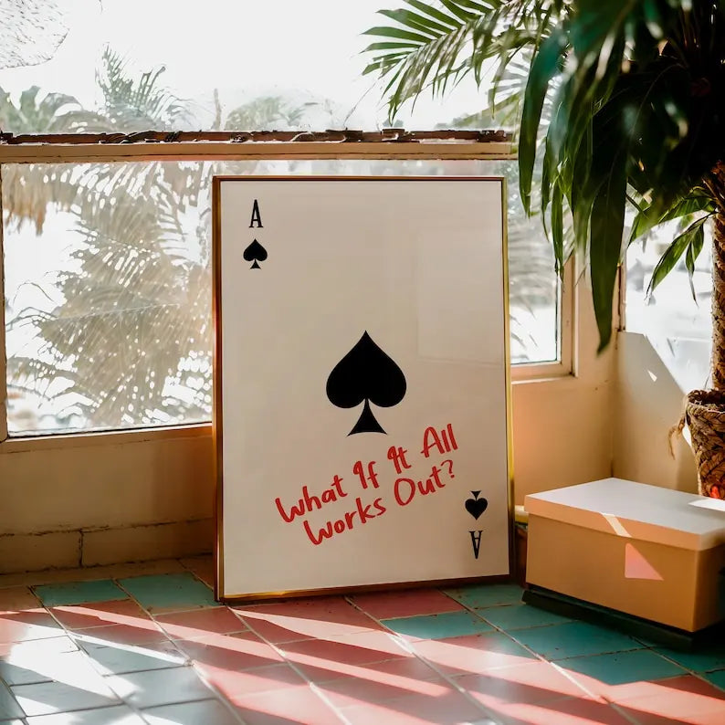 Large framed poster with a spade symbol and text in a room with plants and a window.