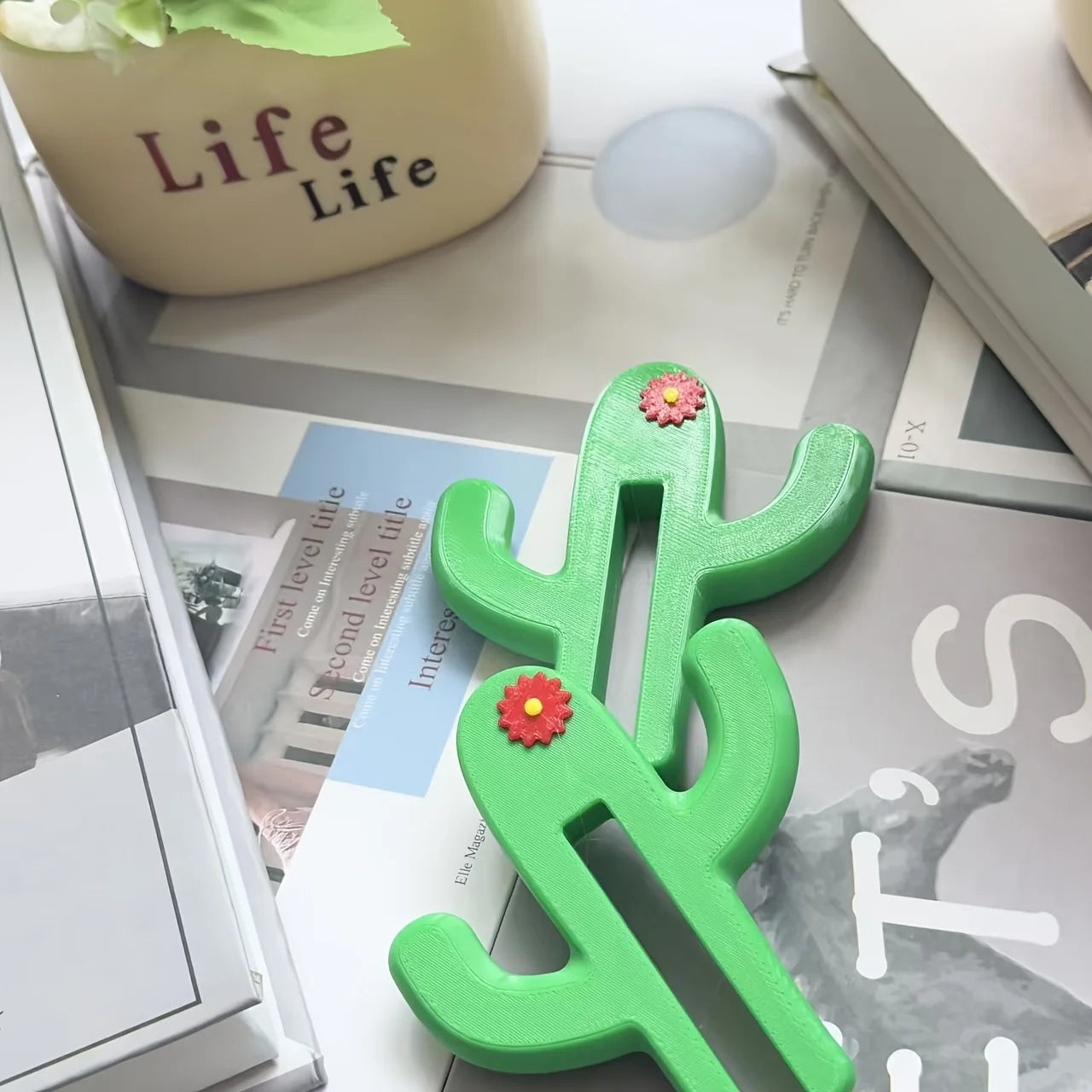 Green cactus shaped bathroom hook hanging over a glass shower door holding towels and accessories close up view 2