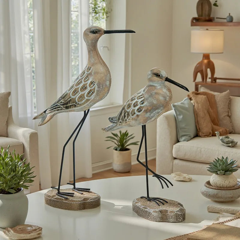 Two decorative bird figures on a coffee table in a living room setting.