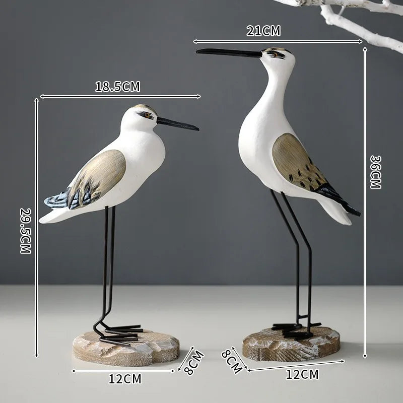 Two bird figurines with measurements on a gray background