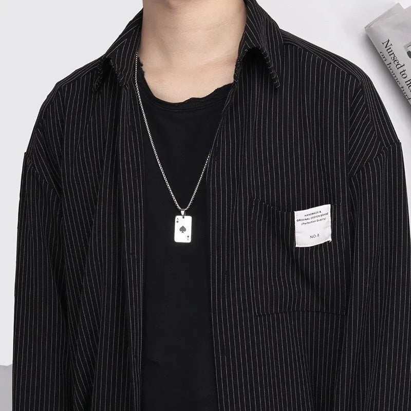 Person wearing a black pinstripe shirt with a pocket label and a necklace.