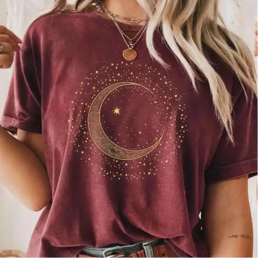 Person wearing a maroon t-shirt with a gold moon design, holding a cup.
