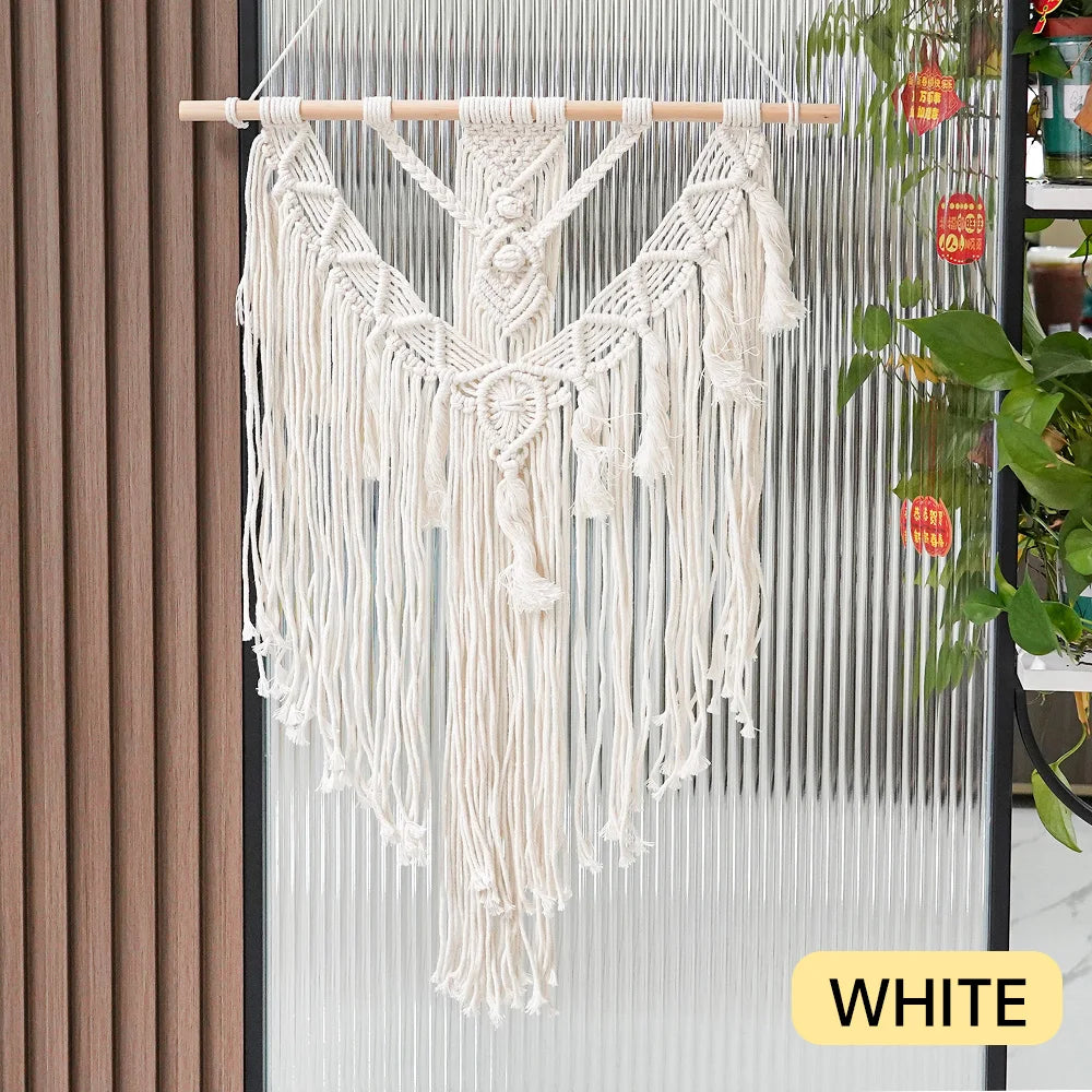 White macrame wall hanging with a wooden rod against a neutral background