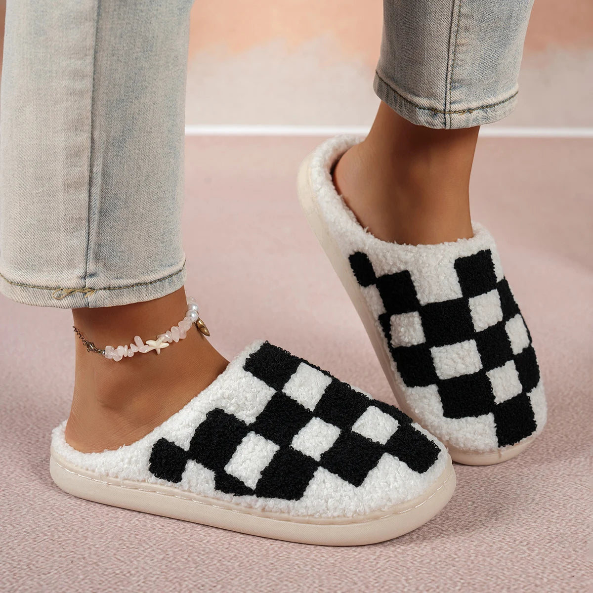 Checkered slippers worn with light blue jeans on a pink background