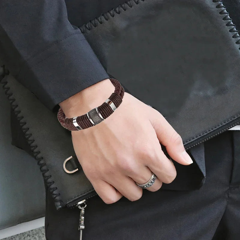 Hand wearing a bracelet with a ring, holding a black leather bag.