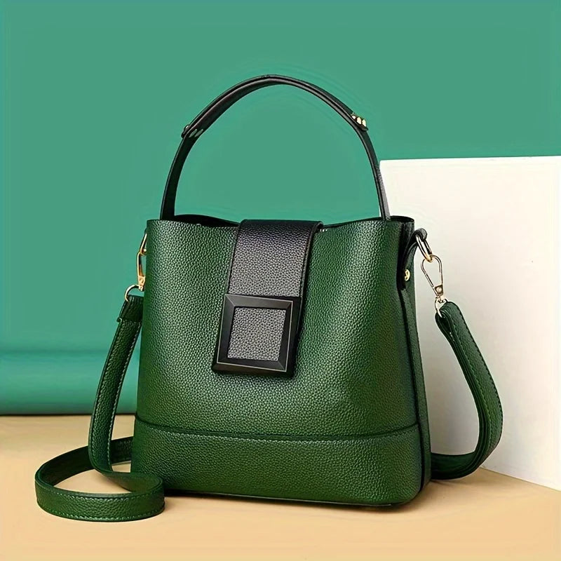 Green handbag with black accents on a light beige surface against a teal background