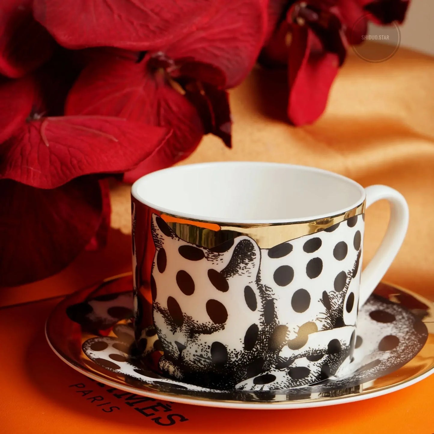 Polka dot coffee cup and saucer with gold trim on a red floral background