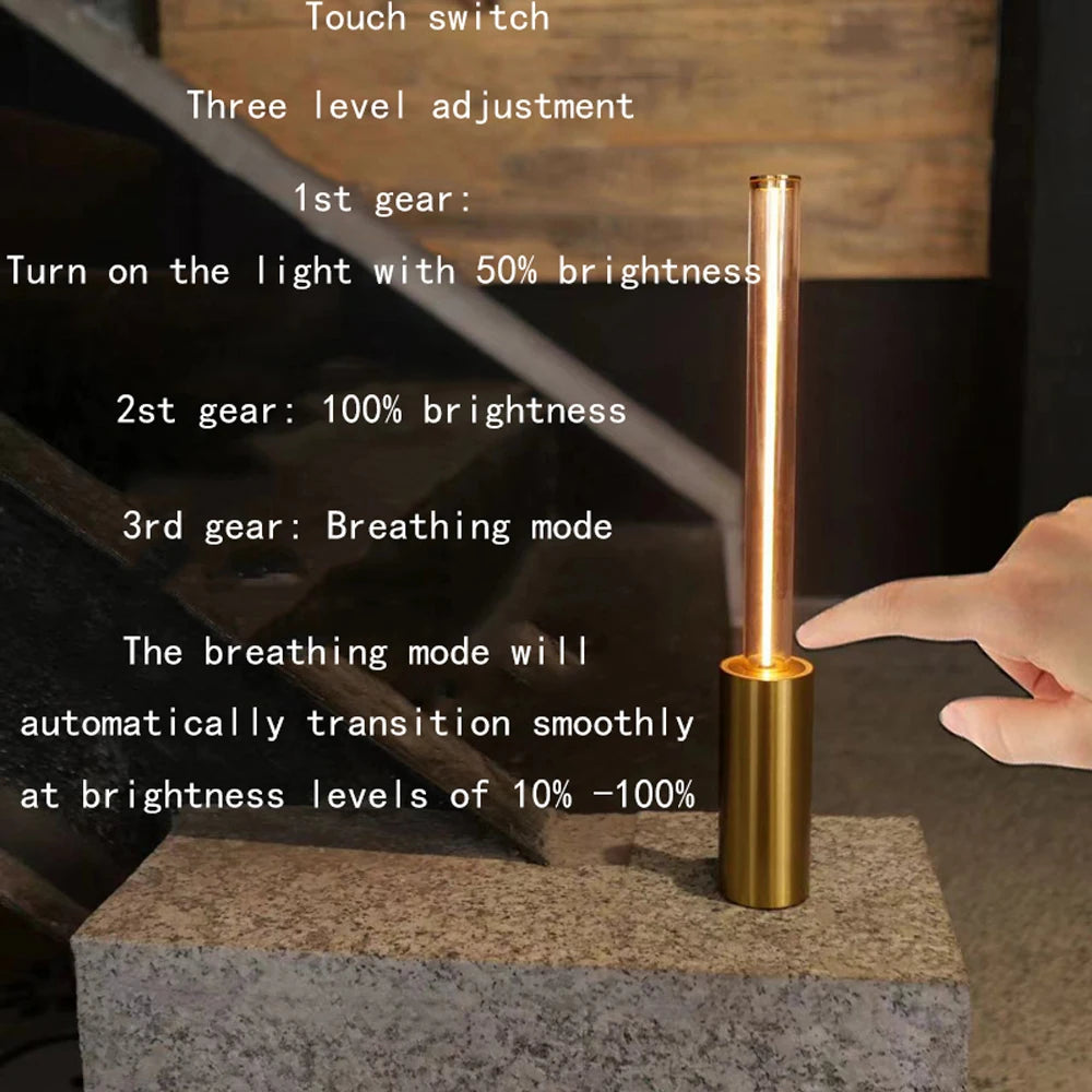 Gold cylindrical light with touch switch and text explaining its features on a stone surface.