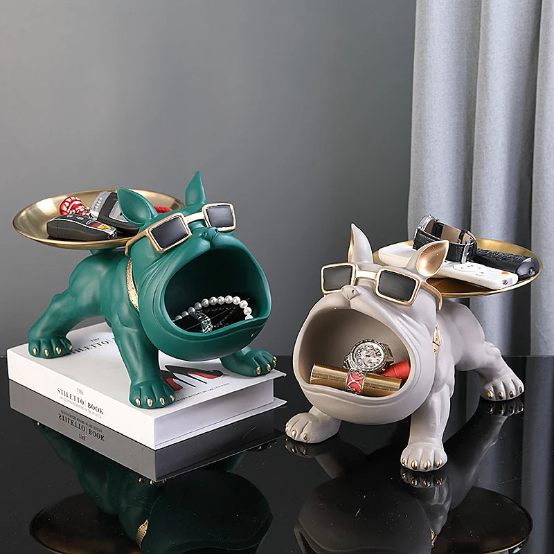 Two decorative dog figurines with tray tops on a dark surface.