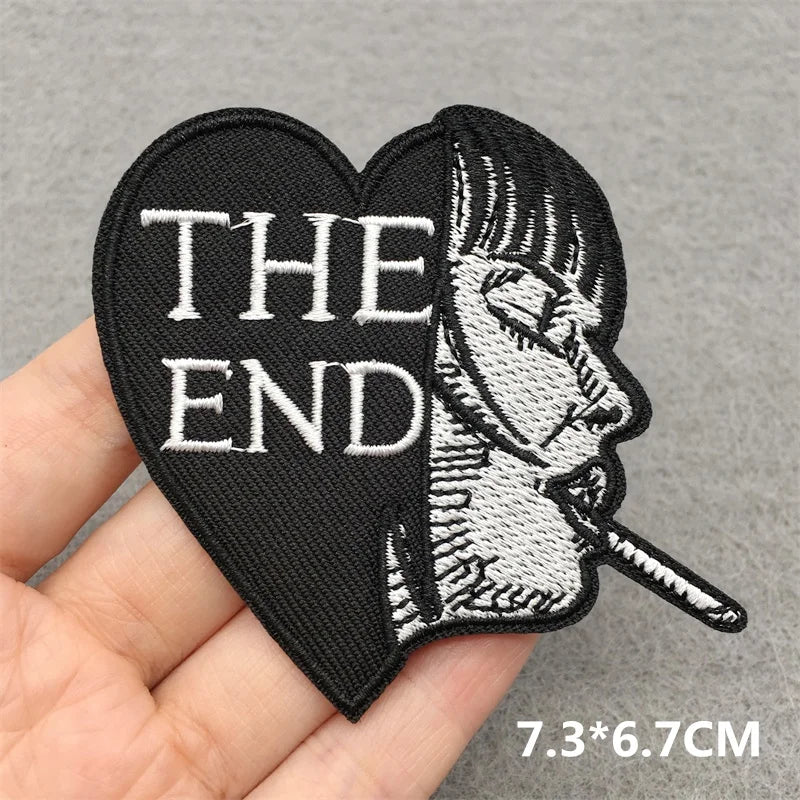 Heart-shaped patch with 'THE END' text and a smoking figure on a gray background