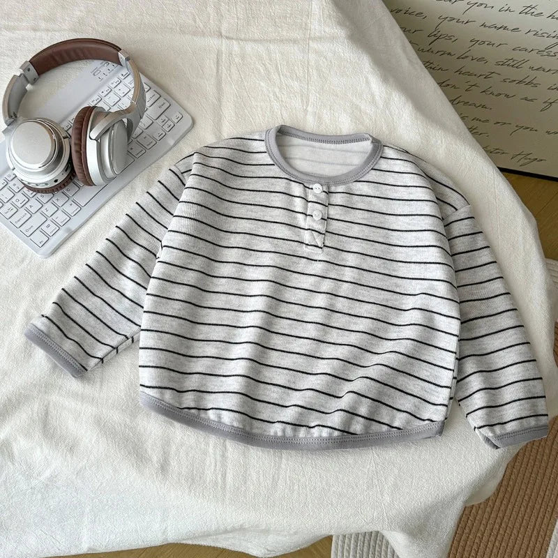 Striped baby shirt on a white surface with headphones and a keyboard.