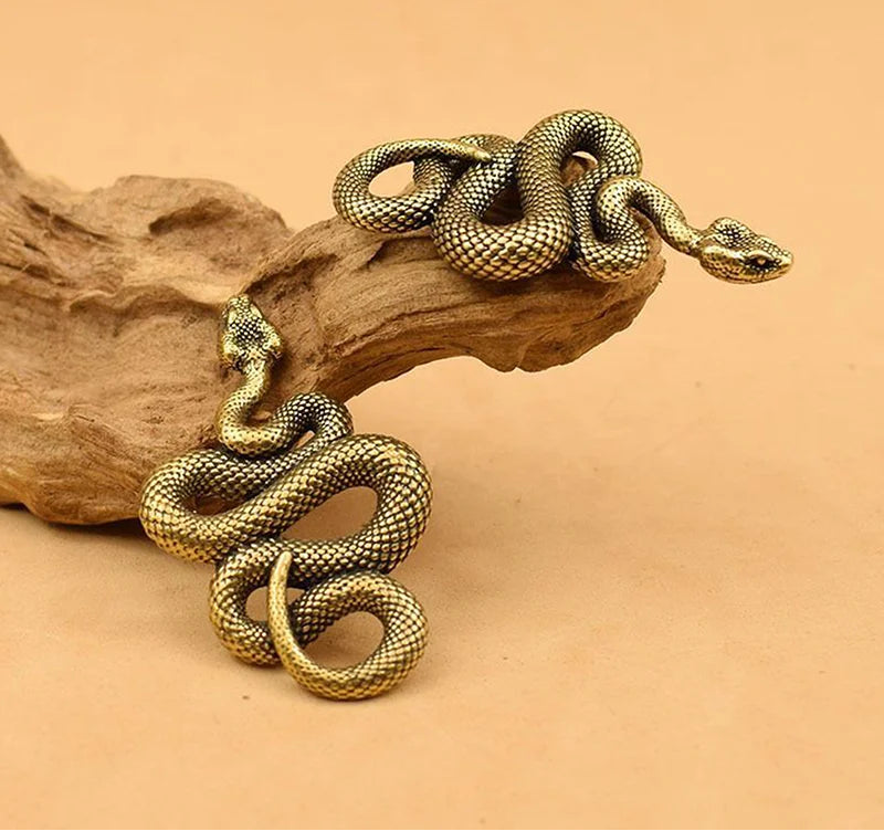 Gold snake-shaped bracelet on a wooden surface with a beige background