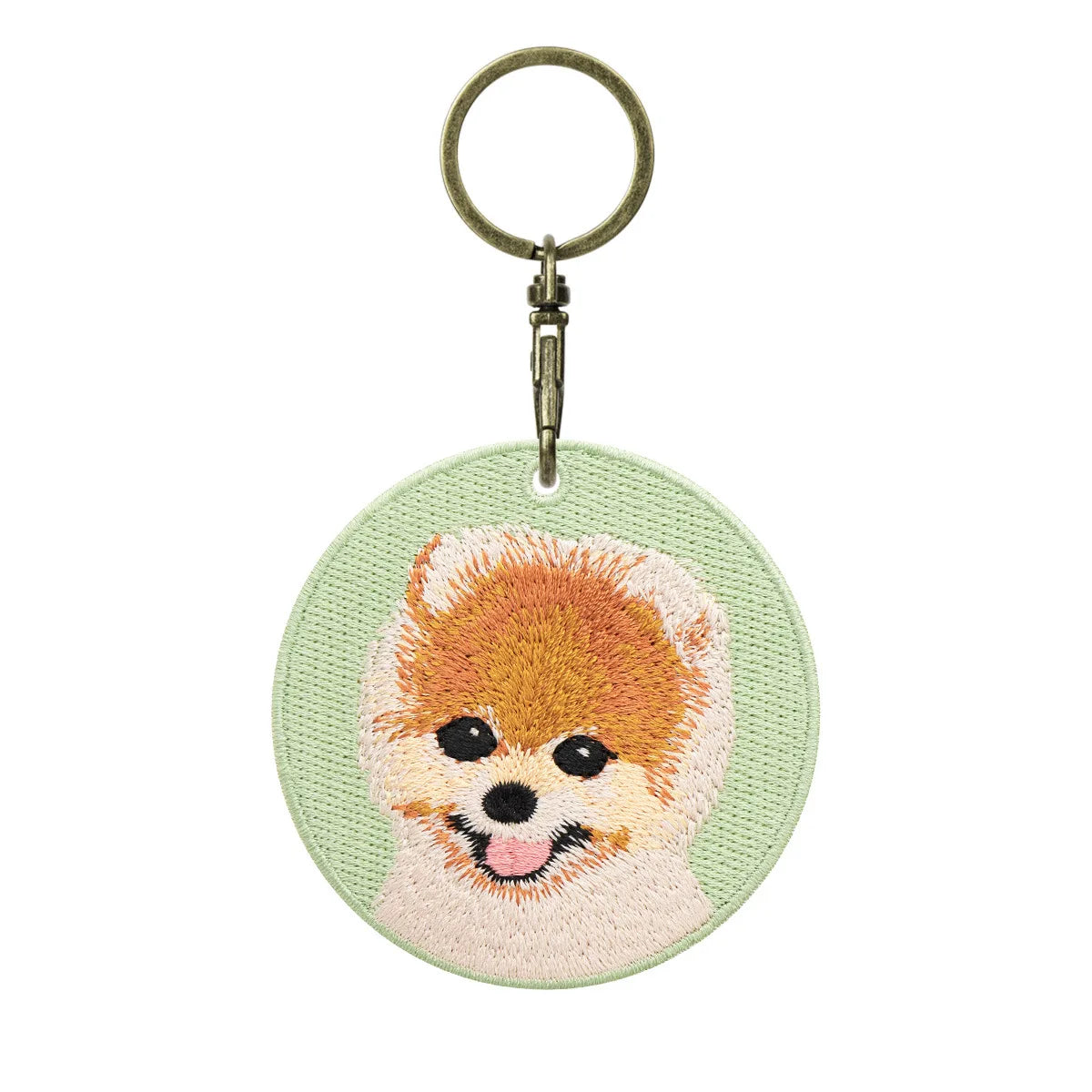 Keychain with embroidered dog face design on a light green background