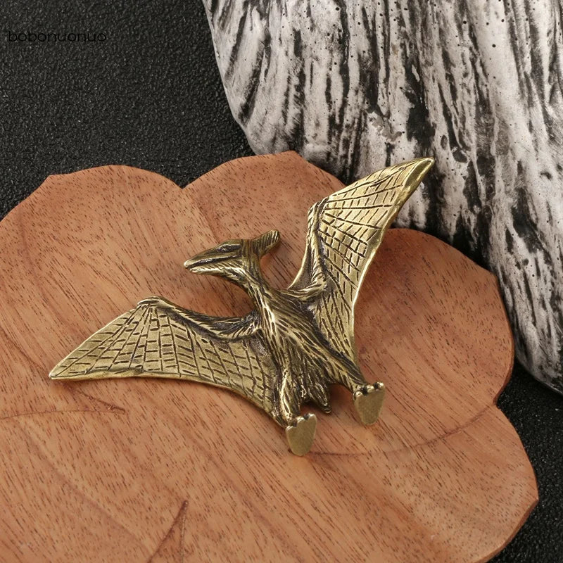 Bronze pterodactyl figurine on a wooden surface with a textured background