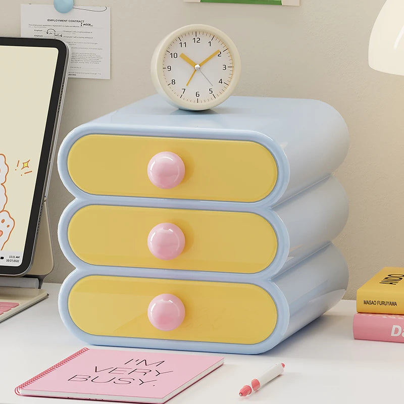 Pastel-colored three-drawer organizer with pink knobs on a desk.