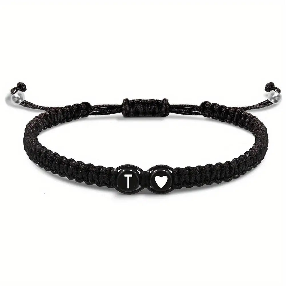 Black braided bracelet with a heart and letter 'T' charm on a white background