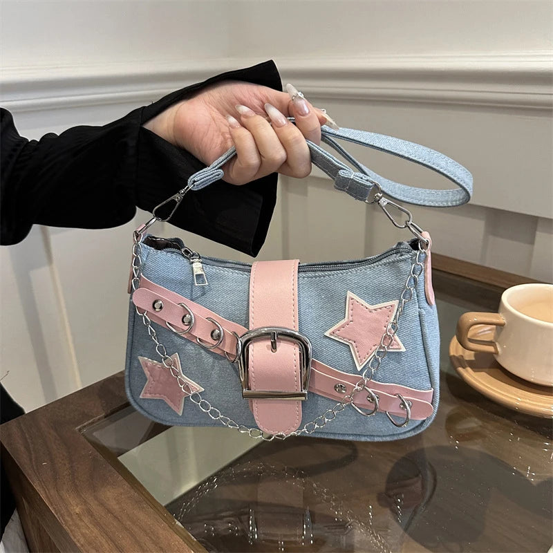 Light blue denim shoulder bag with pink star patches, decorative chain detail and buckle, designed as a stylish Y2K-inspired women's handbag.