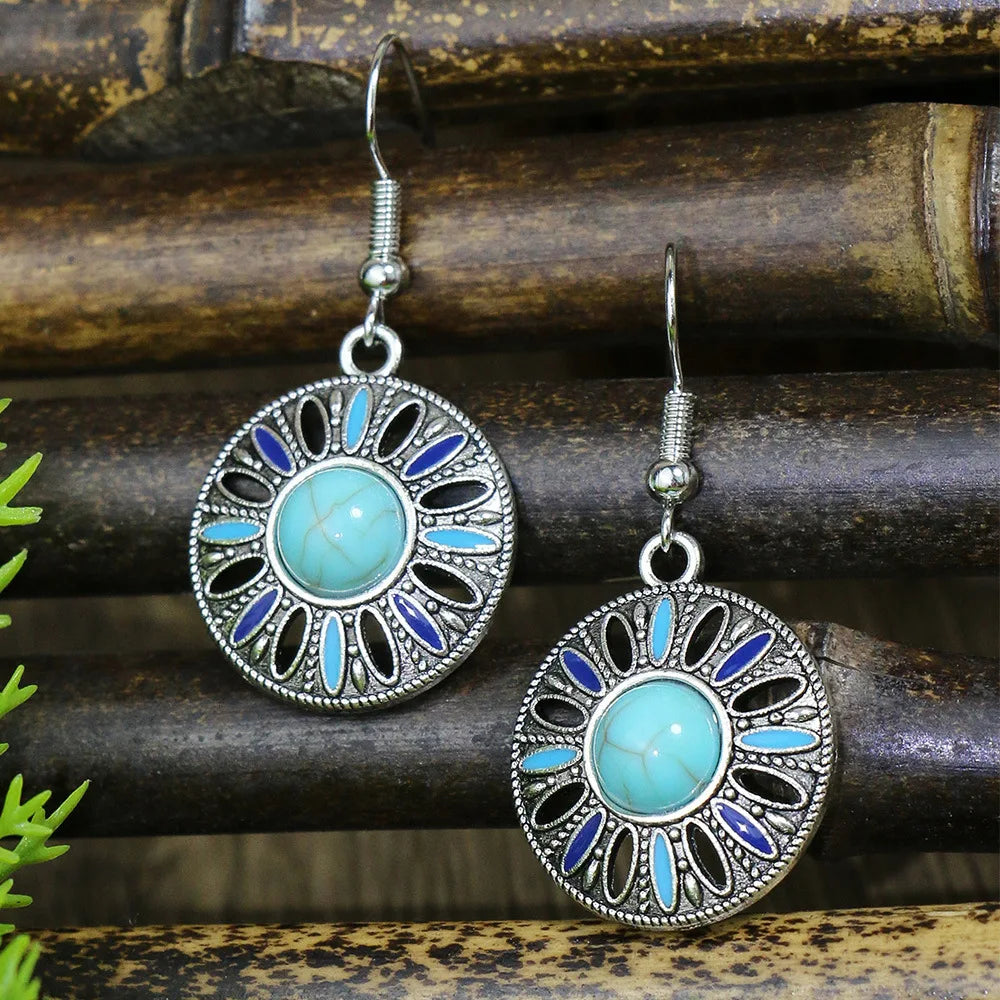 Pair of earrings with turquoise stones and silver accents on a wooden surface