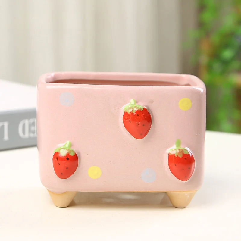 Pink ceramic planter with strawberry designs on a light background
