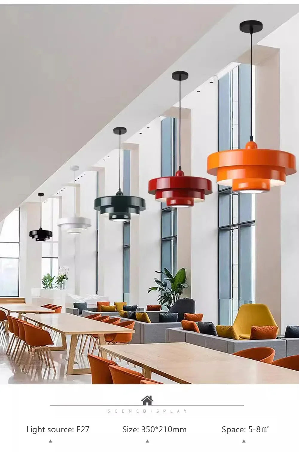Modern office interior with orange and black pendant lights hanging above a long table.