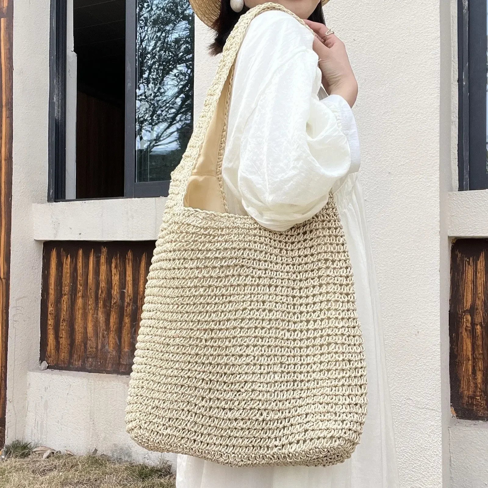 Person holding a beige woven bag outdoors.