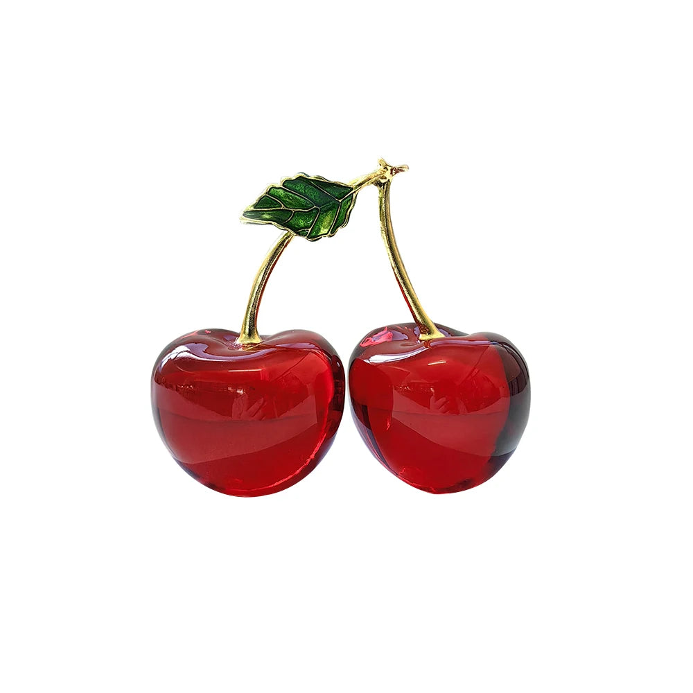 Red cherry ornament with gold stems on a white background