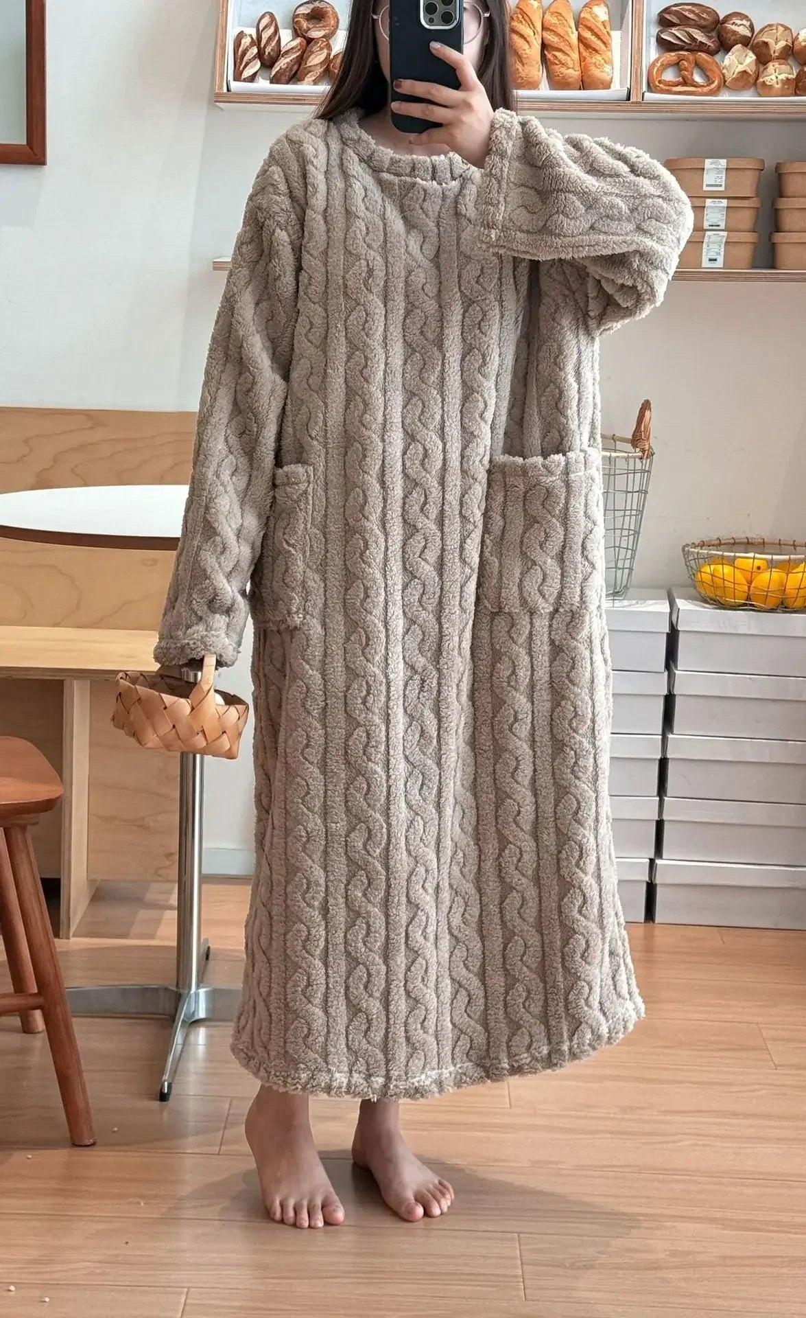 Person wearing a long cable knit sweater in a kitchen setting.
