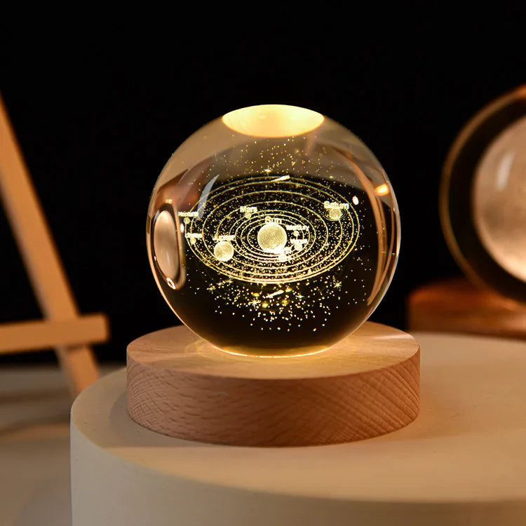 Glass ball with solar system model on a wooden base against a dark background