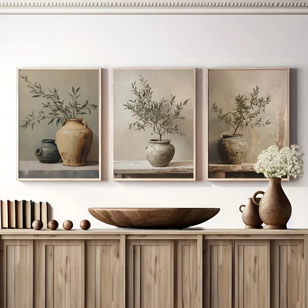 Three framed prints of potted plants on a wall above a wooden cabinet with decorative items.