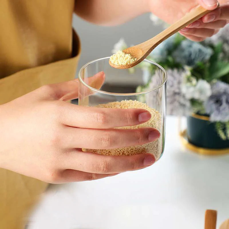 Person holding a glass of granola with a wooden spoon, blurred background