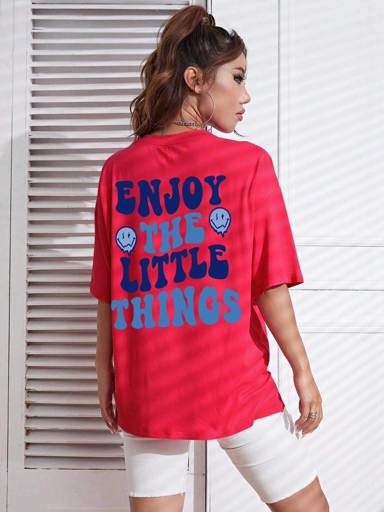 Person wearing a red t-shirt with 'Enjoy The Little Things' text on the back.