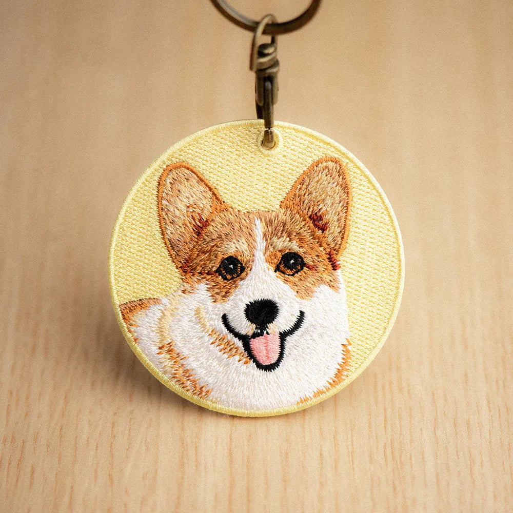 Embroidered keychain with a corgi design on a wooden surface