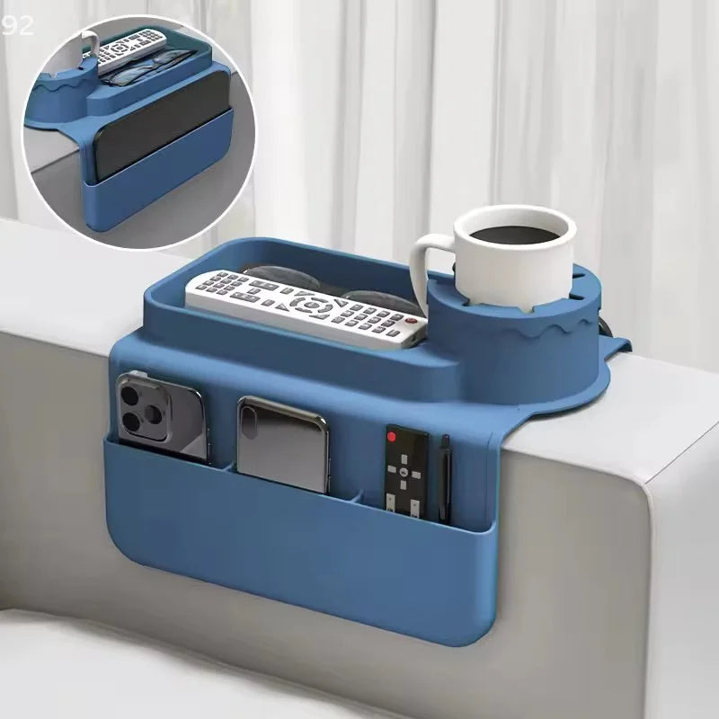 Silicone sofa armrest cup holder holding a mug, remote controls and smartphones on a couch.
