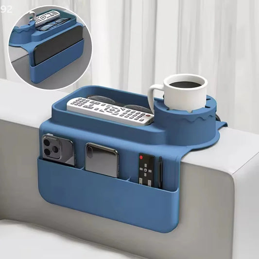 Silicone sofa armrest cup holder holding a mug, remote controls and smartphones on a couch.