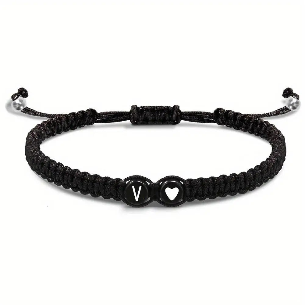 Black braided bracelet with heart and letter 'V' charm on a white background