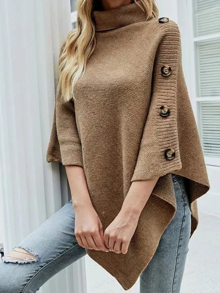 Women’s oversized brown poncho sweater with turtleneck and button sleeve detail styled with jeans