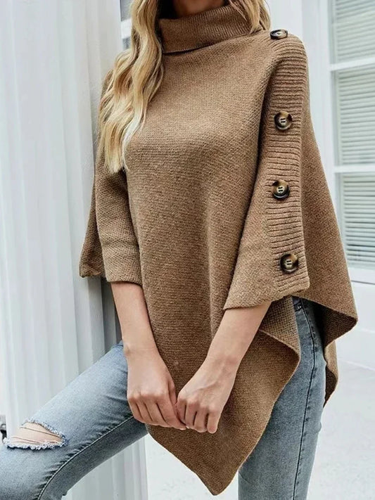 Women’s oversized brown poncho sweater with turtleneck and button sleeve detail styled with jeans