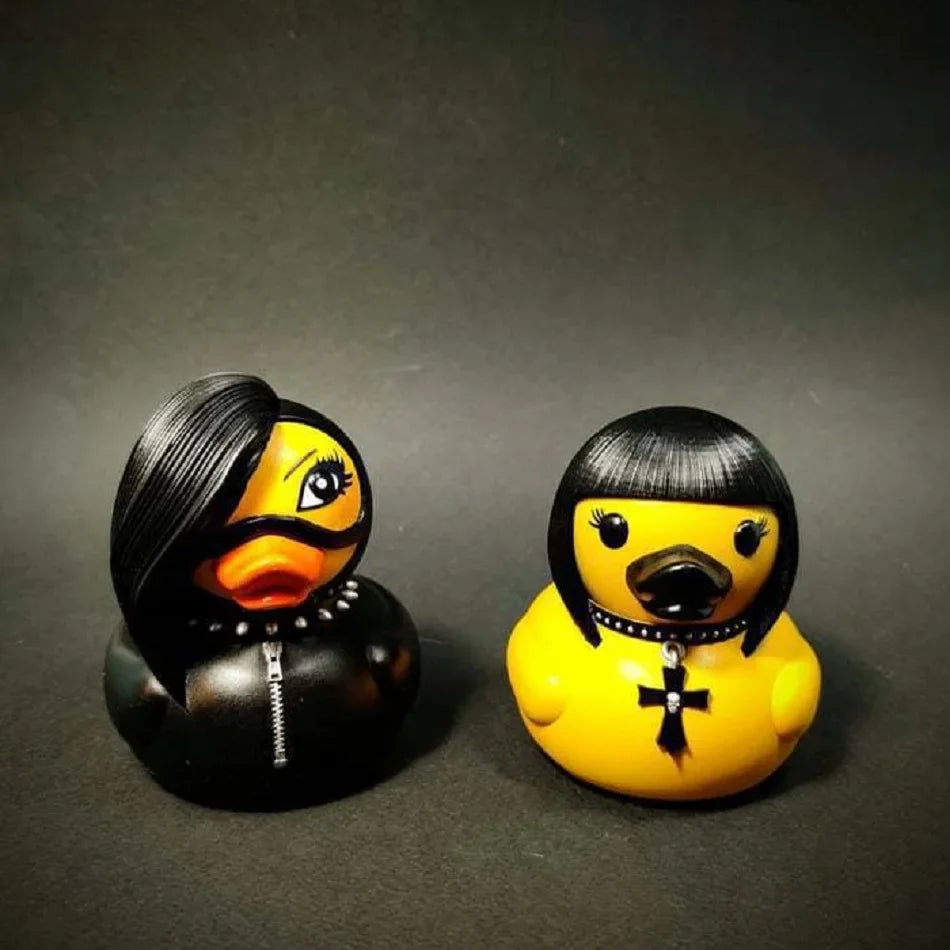 Two rubber duckies, one black and one yellow, with styled hair and accessories on a dark background.