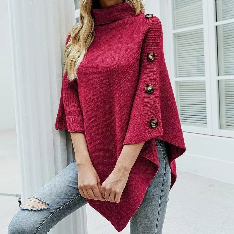 Women’s oversized red poncho sweater with turtleneck and button sleeve detail styled with jeans