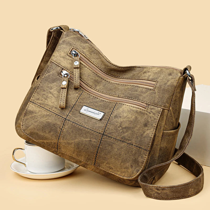 Brown handbag with multiple zippers on a beige background