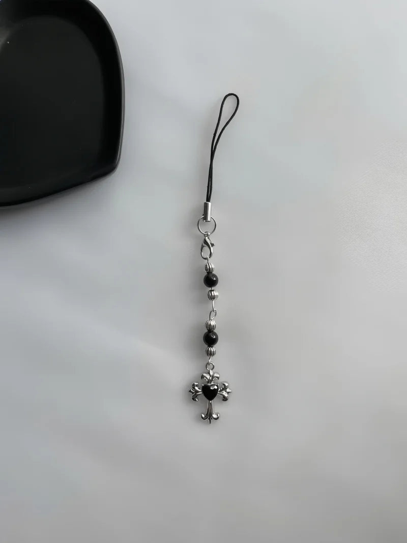 Phone charm with cross and heart pendant on a white background