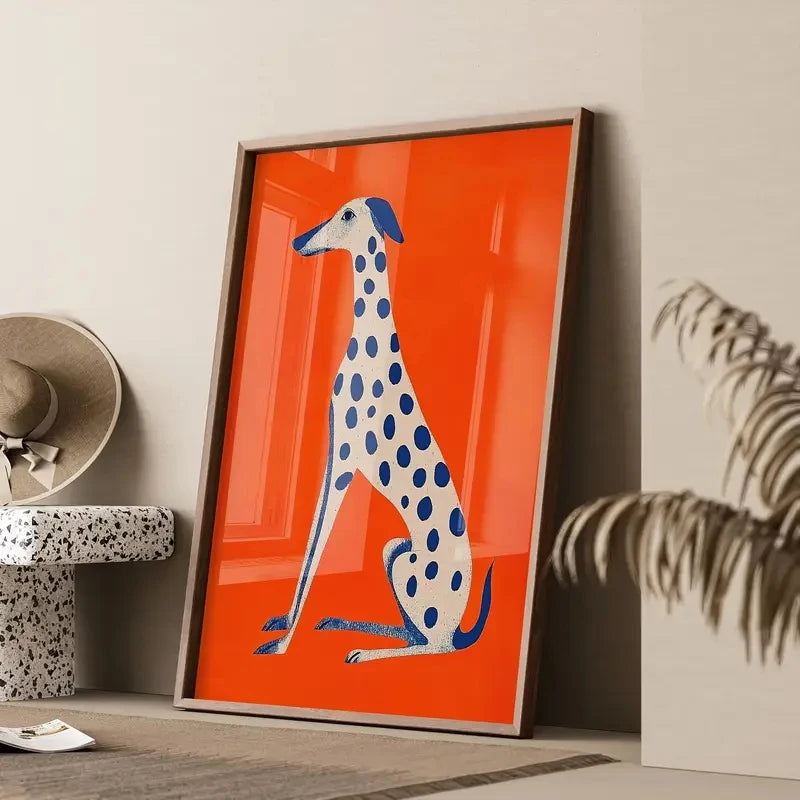 Framed artwork of a blue and white spotted dog on an orange background, leaning against a wall.