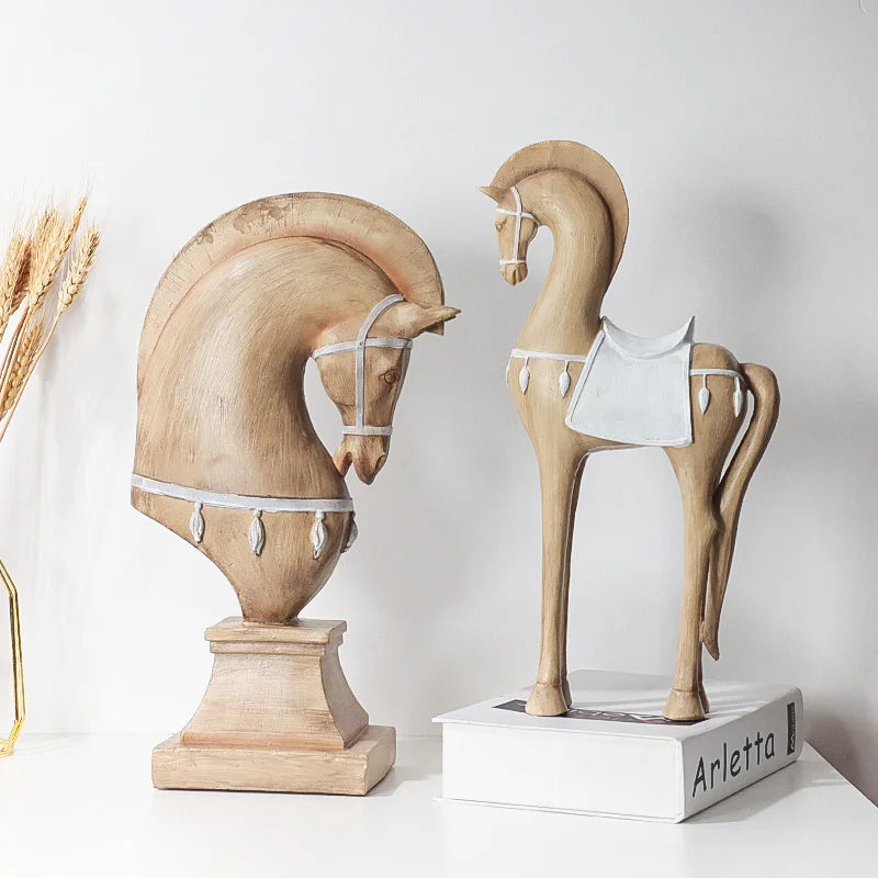 Two wooden horse sculptures on a white surface with a neutral background