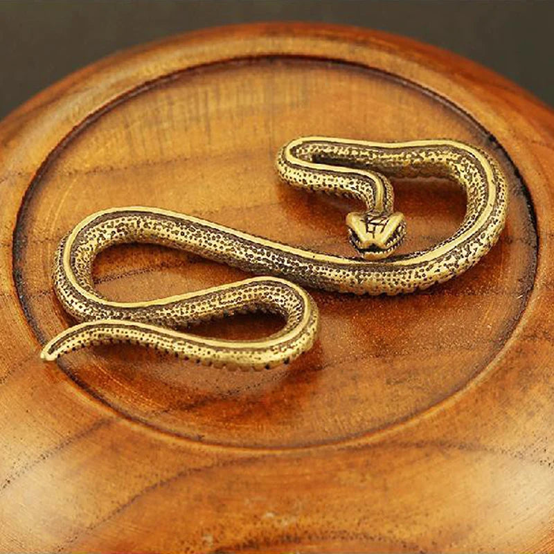 Gold snake-shaped object on a wooden surface