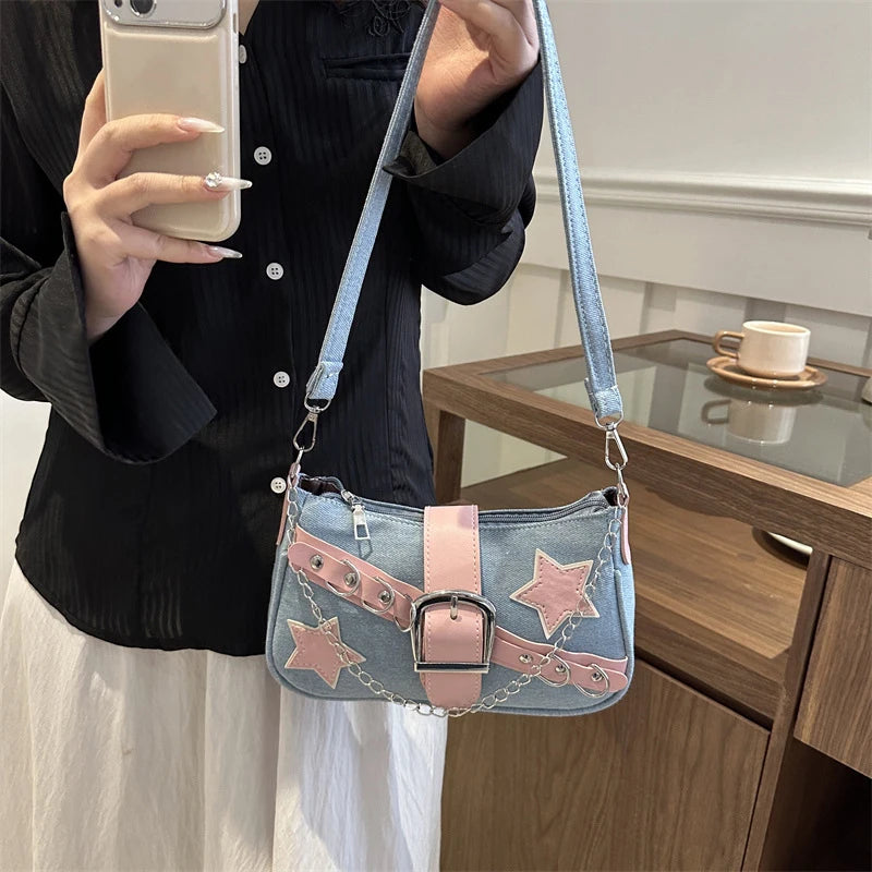 Person holding a denim handbag with pink accents and star designs.