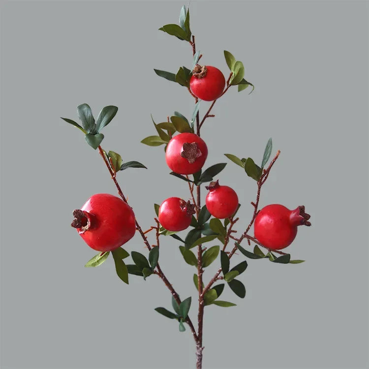 Artificial pomegranate branch with red fruits on a gray background