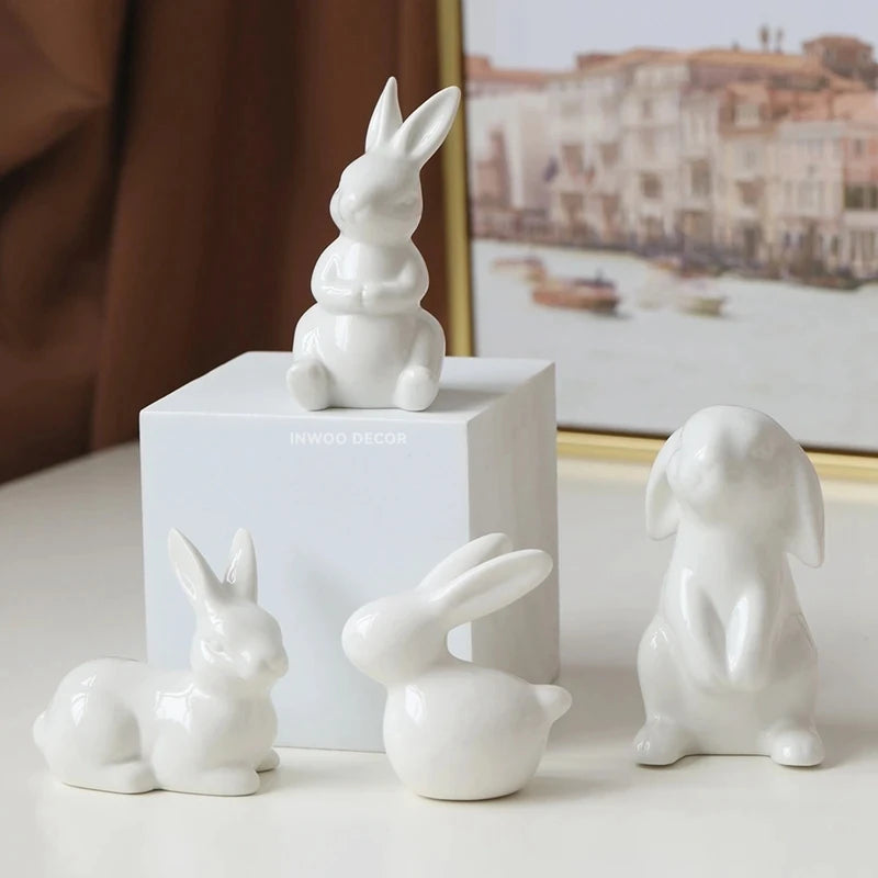Set of white ceramic rabbit sculptures on a light surface with a blurred background