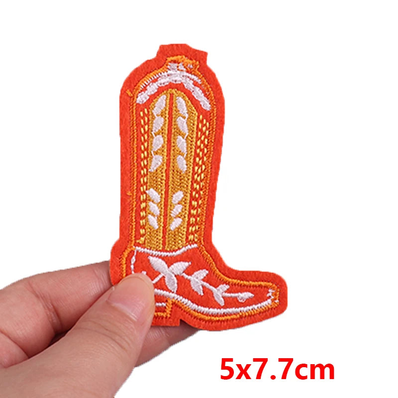 Embroidered patch of a cowboy boot held by a hand with dimensions indicated.