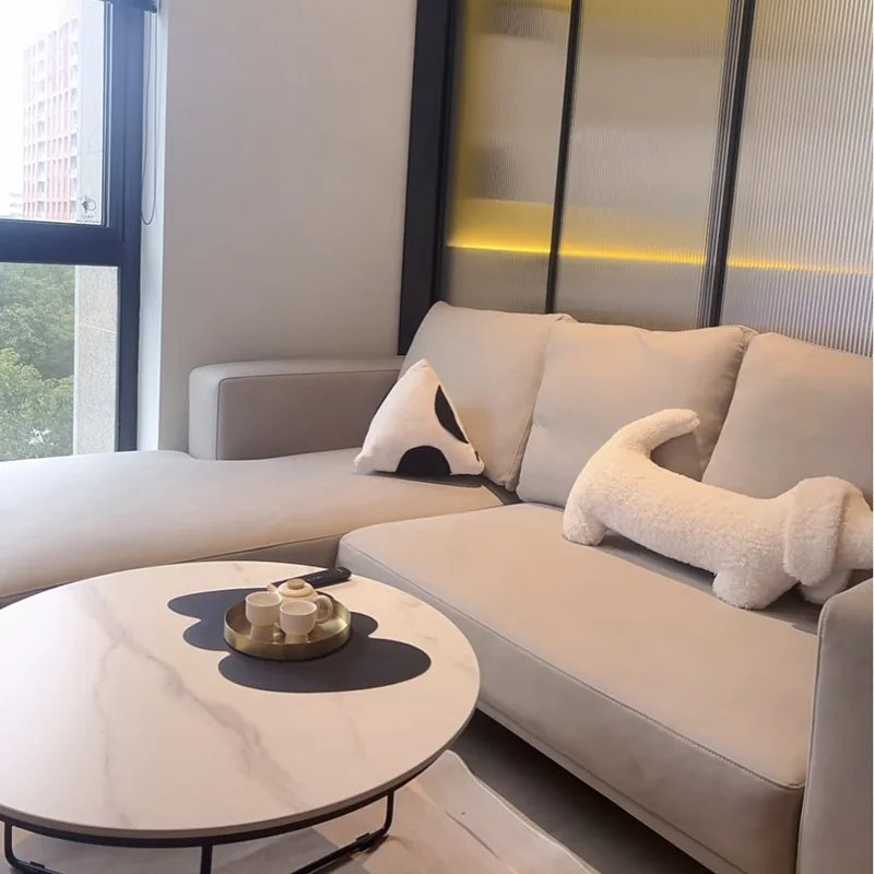 dachshund-shaped cushion in a Modern living room with a beige sectional sofa and a round coffee table.