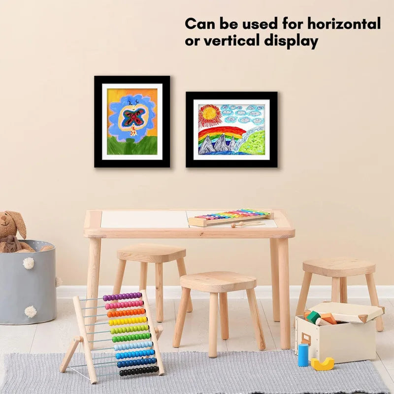 Children's play area with a table, stools, and toys, featuring framed artwork on the wall.